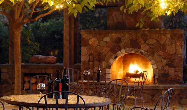 The guest house patio with fireplace and wine bottles on table.